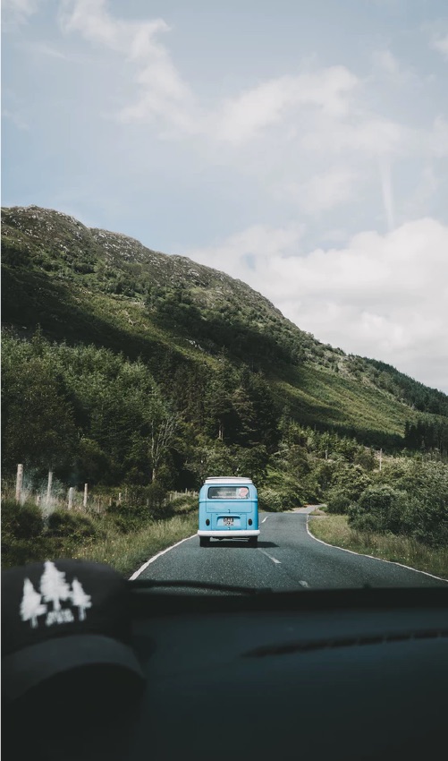 A blue car driving through winding mountains.