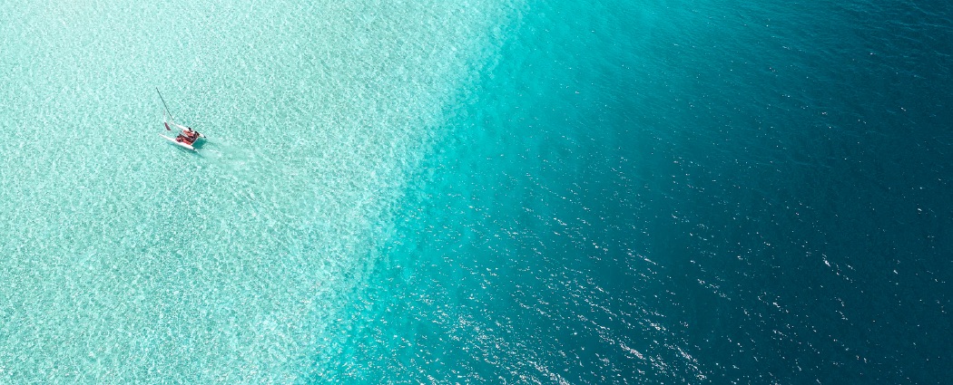 A catamaran sailing on crystal clear water.