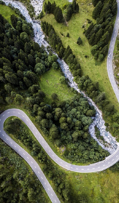 An overhead shot of a winding road, crossing a river bed.