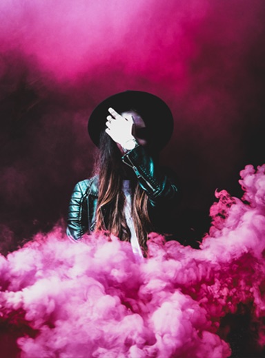 A woman standing in pink smoke.